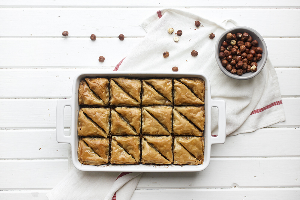 Chocolate Hazelnut Baklava - Flaky, crispy phyllo dough layered with hazelnuts and bittersweet chocolate chocolate, topped with a honey-cocoa nib syrup that provides a twist on the traditional walnut/almond greek baklava dish #baklava #dessert #dessertrecipe #sweetdessert #phyllodough #phyllo #hazelnut #chocolate 