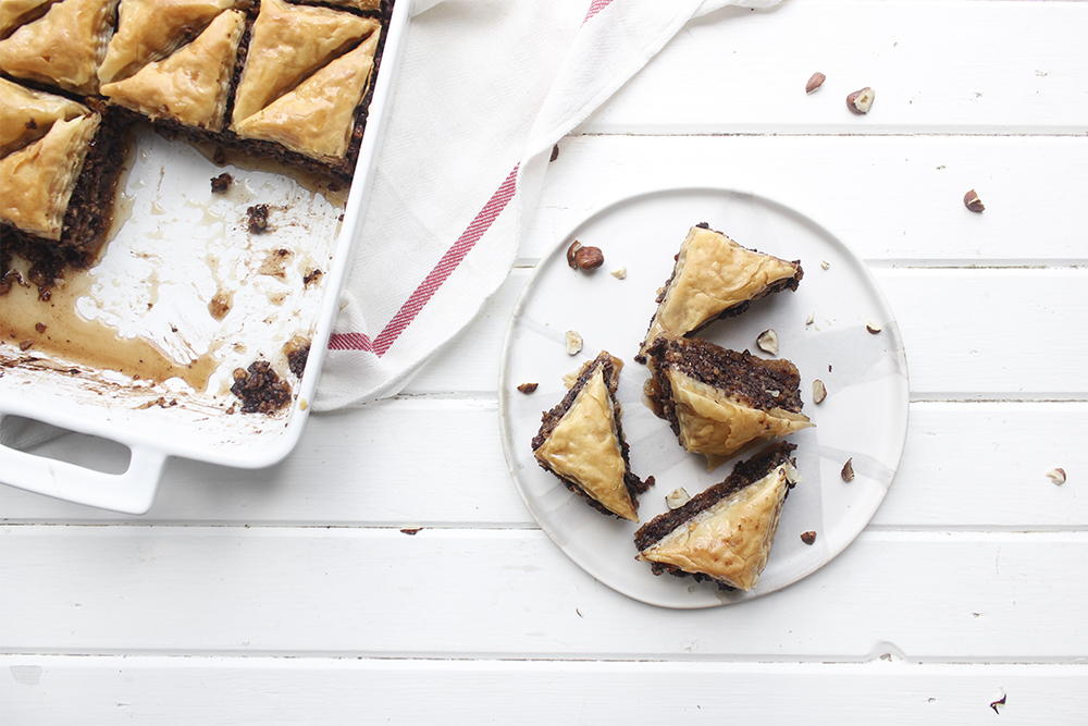 Chocolate Hazelnut Baklava - Flaky, crispy phyllo dough layered with hazelnuts and bittersweet chocolate chocolate, topped with a honey-cocoa nib syrup that provides a twist on the traditional walnut/almond greek baklava dish #baklava #dessert #dessertrecipe #sweetdessert #phyllodough #phyllo #hazelnut #chocolate 