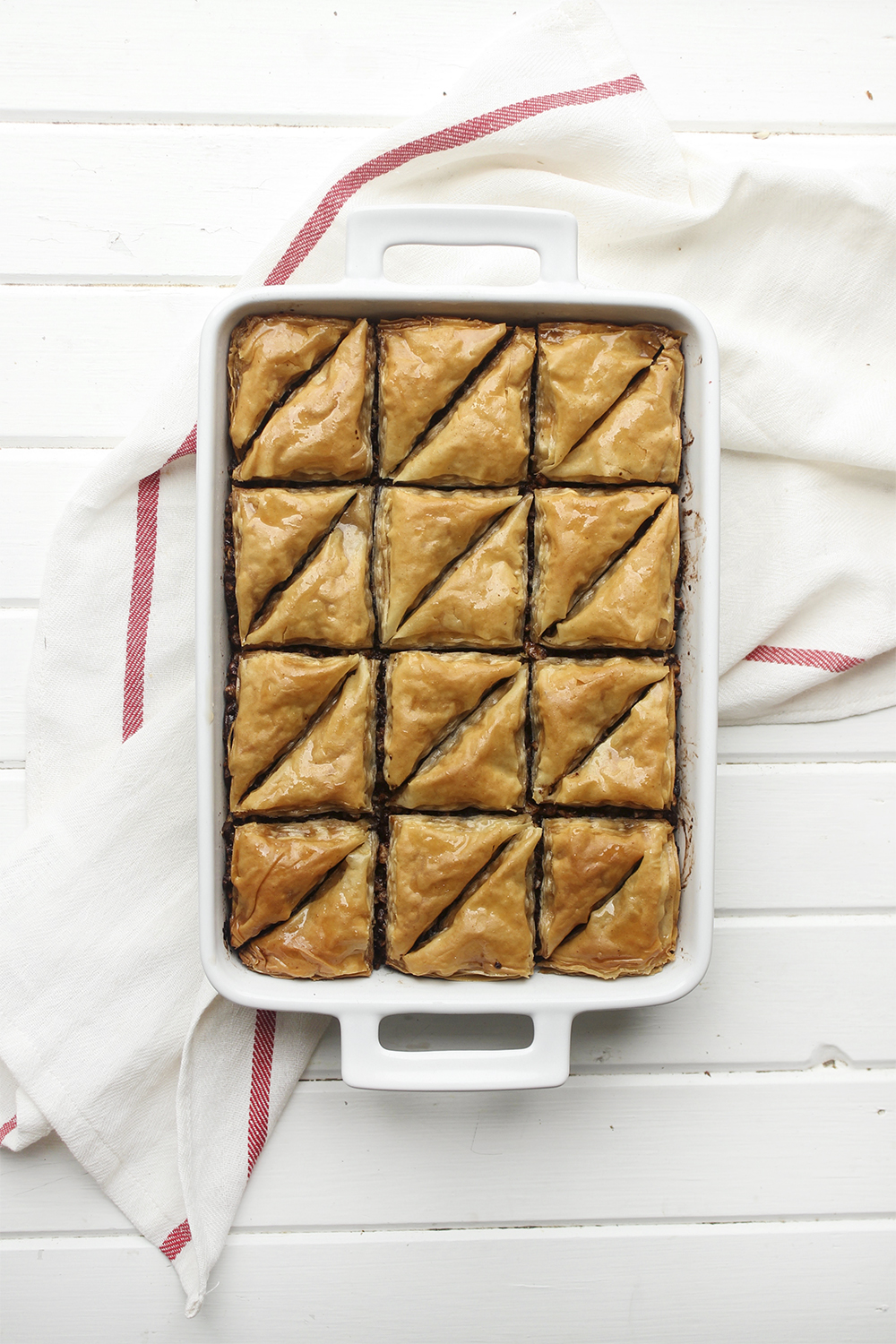 Chocolate Hazelnut Baklava - Flaky, crispy phyllo dough layered with hazelnuts and bittersweet chocolate chocolate, topped with a honey-cocoa nib syrup that provides a twist on the traditional walnut/almond greek baklava dish #baklava #dessert #dessertrecipe #sweetdessert #phyllodough #phyllo #hazelnut #chocolate 