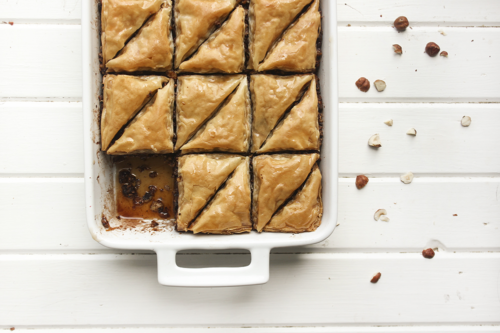 Chocolate Hazelnut Baklava - Flaky, crispy phyllo dough layered with hazelnuts and bittersweet chocolate chocolate, topped with a honey-cocoa nib syrup that provides a twist on the traditional walnut/almond greek baklava dish #baklava #dessert #dessertrecipe #sweetdessert #phyllodough #phyllo #hazelnut #chocolate 